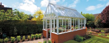 A White Hartley Botanic Greenhouse With A Brick Base