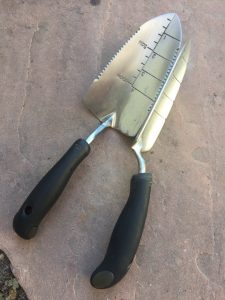 OXO's trowels are stainless stee; the narrow transplanting trowel is turned on its side here to better show the cushioned handle. 